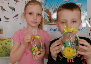 Chłopiec i dziewczynka pokazują udekorowane akrylowe jajka.